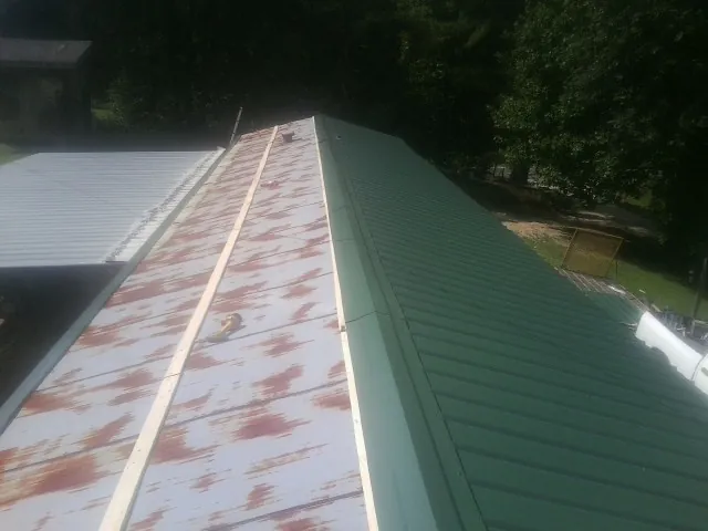 Old rusted panels beside newly installed green metal roofing — Wind Damage Roof Repair by Roofing Brothers in Stony Point