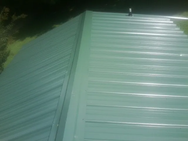 New green metal panels meeting at the ridge of a roof — Flat Roof Repair work by our crew in Stony Point