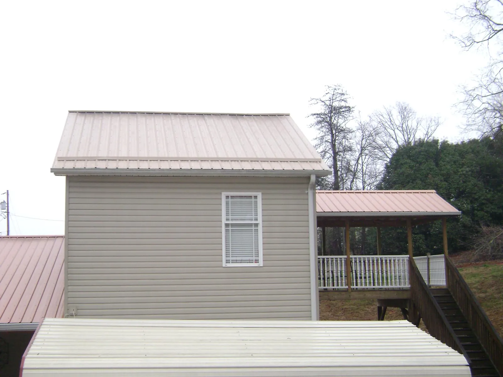 Tan metal roofs on a two story addition and attached porch, from a Roof Replacement job in Stony Point